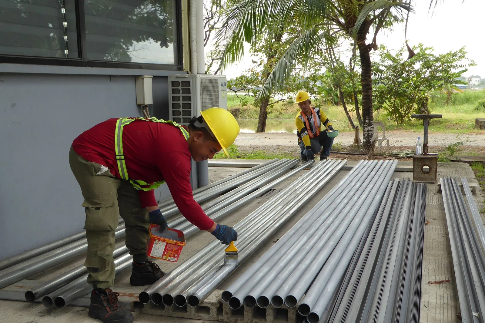Fenêtre en PVC en cours de mise en peinture au pinceau, joints et vitrage protégés par du ruban de masquage